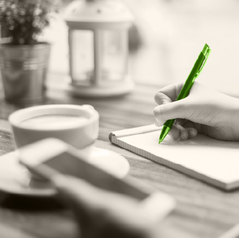 hand writing on paper with a green pen