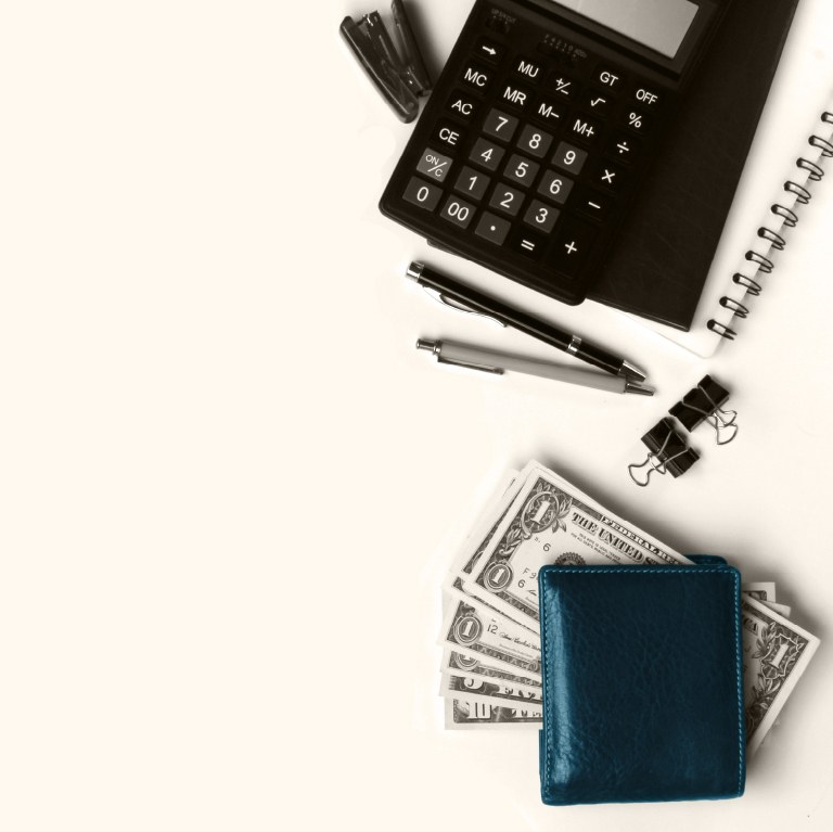 calculator, pens journal , wallet and money  on a table