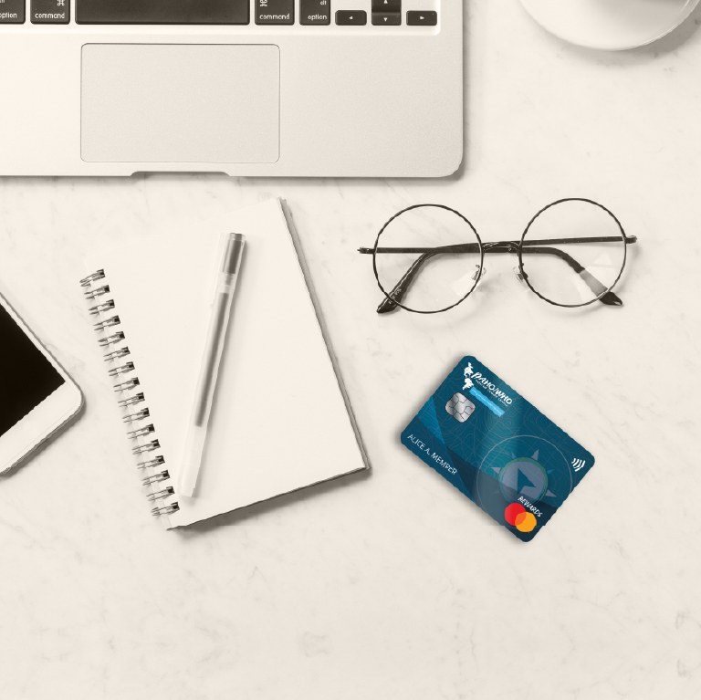 credit card on a desk next to glasses and laptop
