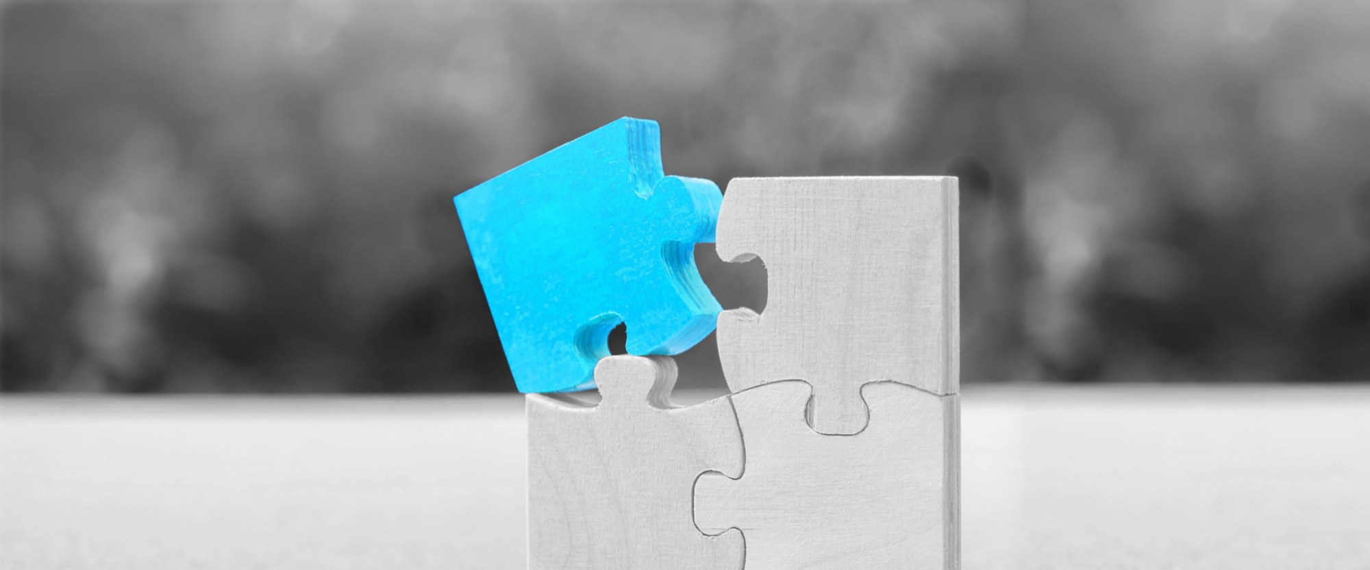 wooden puzzle with someone inserting a cyan blue puzzle piece